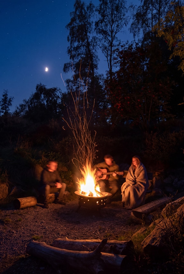 Beleuchtete Feuerstelle und Campingatmosphäre im Anderswo Camp Finsterau bei Nacht