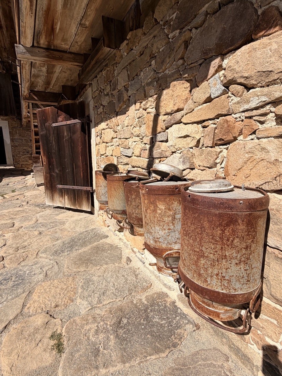 Alte Milchkannen und geöffnete Holztür am Petzi-Hof im Freilichtmuseum Finsterau